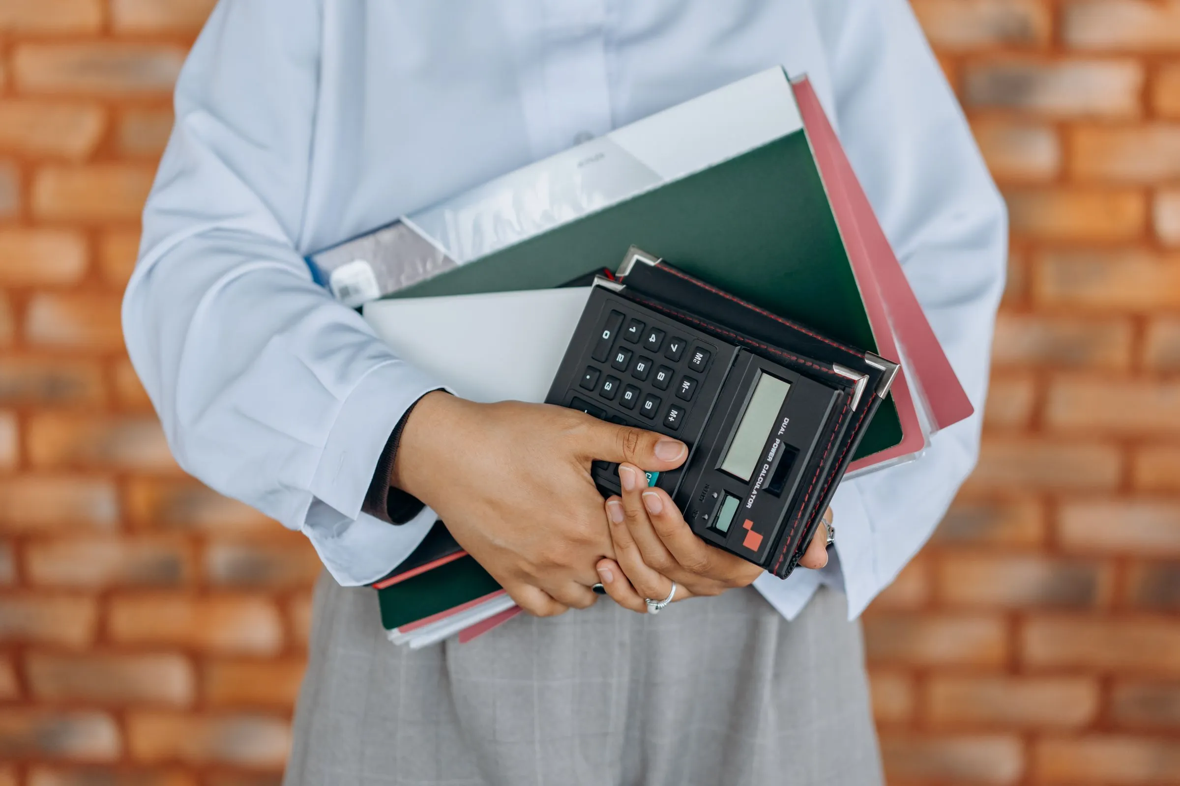 An accountant holding client folders and a calculator